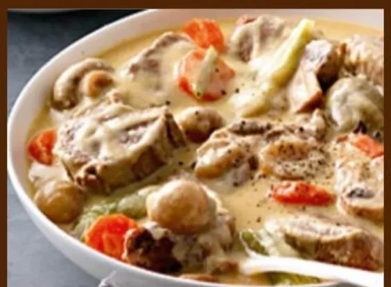 Blanquette de veau à l’ancienne servie dans une assiette blanche, garnie d'herbes fraîches.