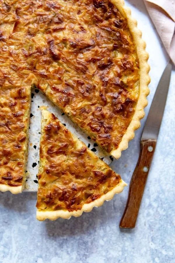 Tarte aux poireaux garnie de légumes frais, prêtes à être servies.