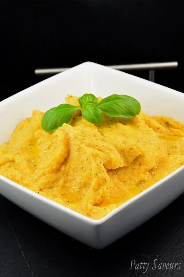 Purée de panais et carottes servie dans un bol blanc, garnie d'herbes fraîches