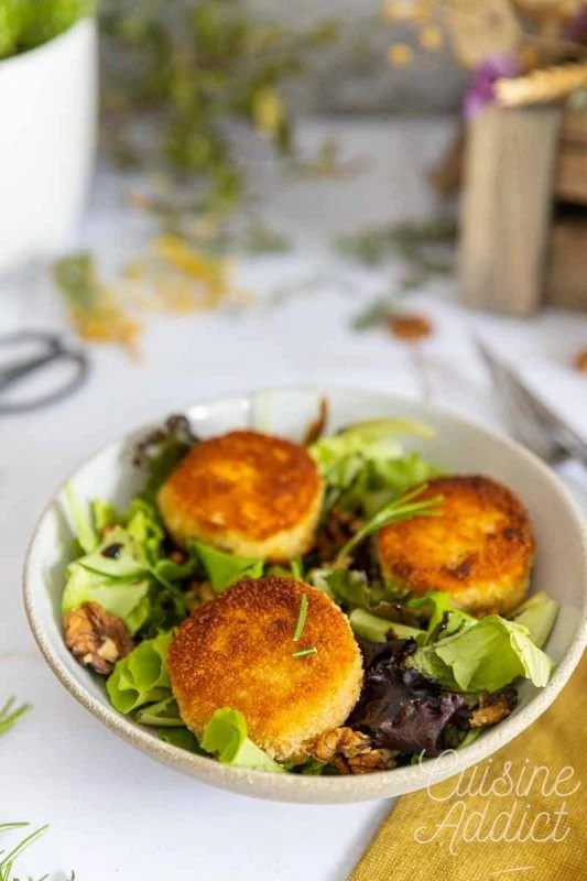 Salade au chèvre chaud garnie de noix et de miel sur une assiette élégante.