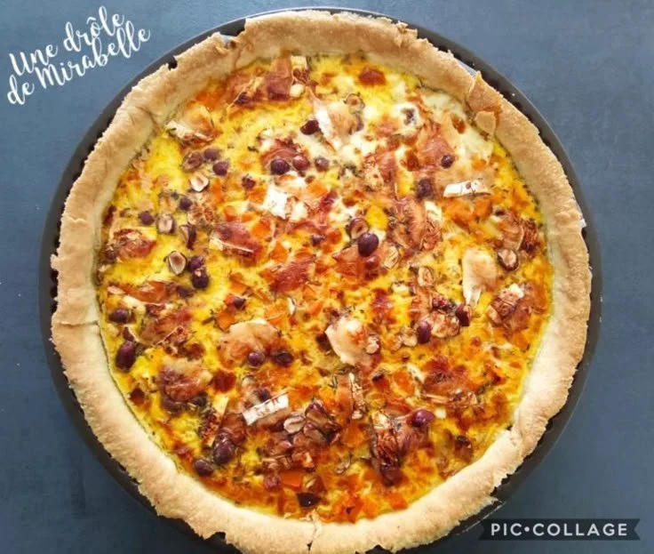 Tarte au potimarron garnie de chèvre et de noisettes sur une table en bois.
